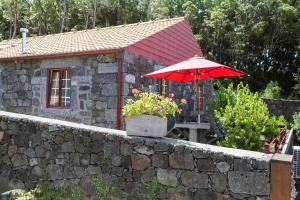 um guarda-chuva vermelho sentado em cima de uma parede de pedra em Aldeia das Adegas em São Roque do Pico