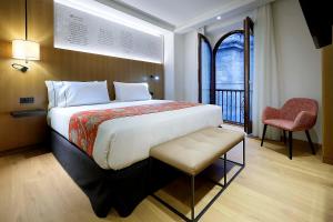 a bedroom with a large bed with a chair and a window at Áurea Catedral by Eurostars Hotel Company in Granada