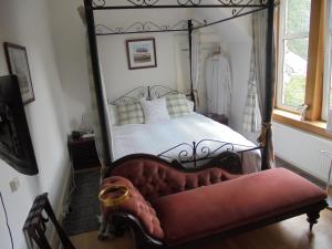 a bedroom with a four poster bed with a red couch at Avondale House in Kingussie