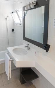 een witte badkamer met een wastafel en een spiegel bij Apartamentos Los Dragos del Norte in Puerto de la Cruz
