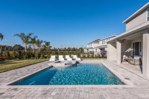 a swimming pool with chairs and a house at Striking Home with Games & Outdoor Kitchen near Disney by Rentyl - 7742F in Orlando
