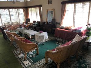 ein Wohnzimmer mit Stühlen, Tischen und Fenstern in der Unterkunft Astani Family Home in Bukittinggi
