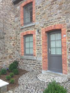 a brick house with a black door and two windows at La Truite Joyeuse in Saint-Hubert
