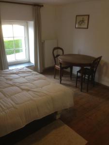 1 dormitorio con cama, mesa y ventana en La Truite Joyeuse, en Saint-Hubert