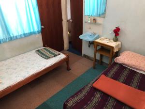 Habitación pequeña con 2 camas y lavamanos en Astani Family Home en Bukittinggi