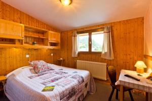 a bedroom with a bed and a table and a window at La Boule de Neige in Samoëns