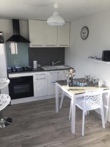 a white kitchen with a white table and chairs at Cosy's'Plage in Kerderff