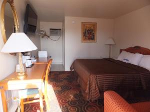 Habitación de hotel con cama y escritorio con lámpara. en Americas Best Value Inn Santa Rosa, New Mexico, en Santa Rosa