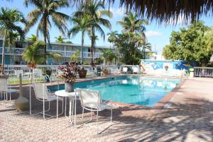 ein Schwimmbecken mit Stühlen und einem Tisch daneben in der Unterkunft Floridian Hotel in Homestead
