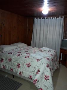 Un dormitorio con una cama con una manta blanca con flores en Casa Modesta, en Campos do Jordão