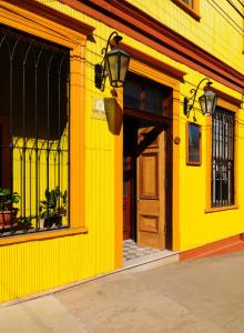 un bâtiment jaune avec une porte en bois et une rue dans l'établissement Hotel Boutique Acontraluz, à Valparaíso