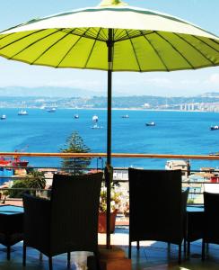 a table and chairs under an umbrella on a balcony at Hotel Boutique Acontraluz in Valparaíso
