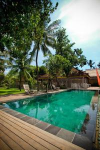 a swimming pool with a wooden deck next to a house at D'Tunjung Resort & Spa in Candidasa