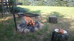 a barbecue grill over a fire in a yard at Przystanek Kaszuby z balią i jacuzzi in Wąglikowice