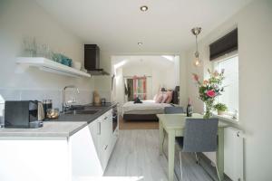 a kitchen with a sink and a table and a bedroom at The Bond Studio FREE PARKING in Zandvoort