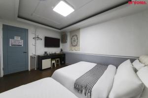 a hotel room with two beds and a television at Sinchon Sisters Hostel in Seoul