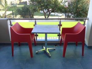 Duas cadeiras vermelhas e uma mesa na varanda em Art Sailing em Vasiliki