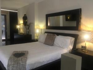 a bedroom with a white bed with a mirror and lamps at Casa Haisea 2 in Caleta De Velez
