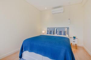 um quarto branco com uma cama com lençóis azuis em Trindade Modern Flat no Porto
