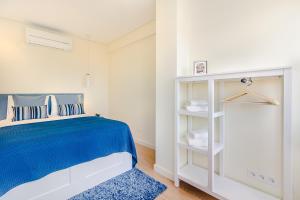 um quarto branco com uma cama azul e uma prateleira branca em Trindade Modern Flat no Porto