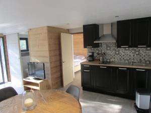 a kitchen with black cabinets and a table with a tv at chez karine et julie in La Rochette