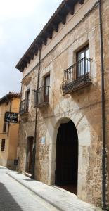 un antiguo edificio de piedra con puerta y balcón en Hotel Fray Tomás, en Berlanga de Duero