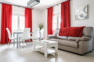 sala de estar con cortinas rojas, mesa y sofá en Casa turística El navego, en Martín Muñoz de las Posadas