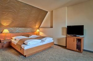 een slaapkamer met een bed en een flatscreen-tv bij Club Hotel Cortina in Wenen