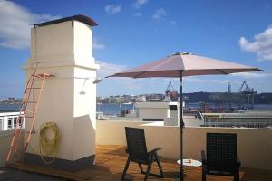 a lighthouse with two chairs and an umbrella on a roof at Apartamento sobre o Rio in Lisbon
