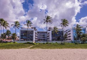 um edifício com palmeiras em frente a uma praia em Unique Beach - Pé Na Areia em João Pessoa