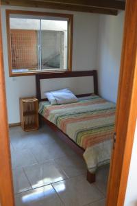 a small bed in a room with a window at Paraiso na Garopaba do Sul ( Farol de Santa Marta) in Jaguaruna