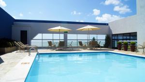 a swimming pool with tables and chairs and umbrellas at Littoral Tambaú Flat in João Pessoa