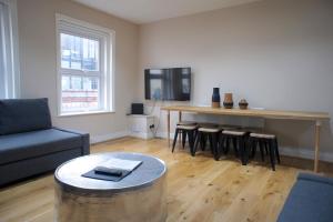 ein Wohnzimmer mit einem Tisch und einer Bar mit Hockern in der Unterkunft Brick Lane Spitalfields Apartment in London