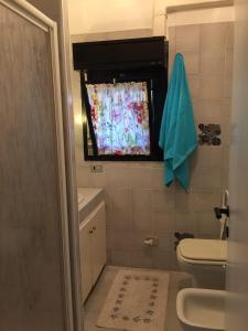 a bathroom with a toilet and a window with a curtain at Appartamento Porto Prile CastiglioneD.P. in Castiglione della Pescaia