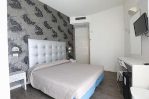 a bedroom with a white bed and a wall at Hotel Daniel's FRONTE MARE in Riccione