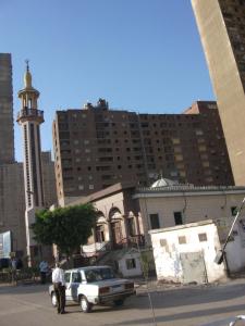 a man standing next to a white car in a city at Al Hamed for Furnished Apartments in Cairo