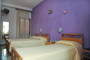 una camera da letto con due letti e una parete viola di Hotel Centrale di Paolo e Cinzia a Loreto