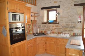 a kitchen with wooden cabinets and a stove top oven at La Vieille Gorce Gîtes in the Vienne in Asnois