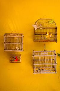 three bird cages hanging on a yellow wall at Hotel Casa Alvarada in Comala