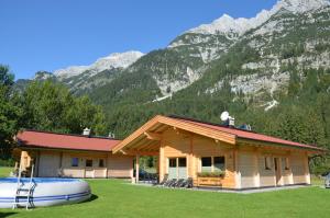 domek z bali z łodzią przed górą w obiekcie Gasthaus-Pension Reiterklause w mieście Leutasch