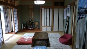 a living room with a wooden table and a red chair at Guesthouse Taihei in Aso
