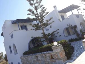 a white building with a tree in front of it at Kapares Studios & Apartments in Agia Anna Naxos