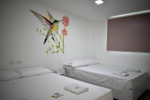 Habitación con 2 camas y un pájaro en la pared en Casa Ilaria en Cartagena de Indias