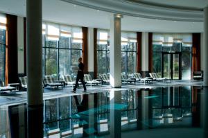 Hotel & Spa Le Pavillon في شاربونيير ليه بان: شخص يمشي في مبنى فيه مسبح