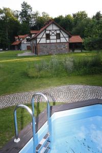 a swimming pool with a house in the background at Leśniczówka Nibork in Nidzica