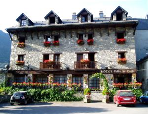 a large stone building with flowers in front of it at Hotel Villa de Torla in Torla-Ordesa