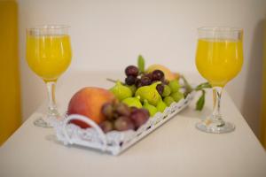 two glasses of orange juice and a basket of fruit on a table at Villa Odobasic Rooms in Mostar