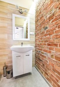 La salle de bains est pourvue d'un lavabo blanc et d'un mur en briques. dans l'établissement Metropolis Apartment, à Toruń