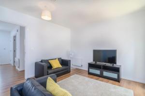 ein Wohnzimmer mit einem Sofa und einem TV in der Unterkunft The Central Lodge in Dartford