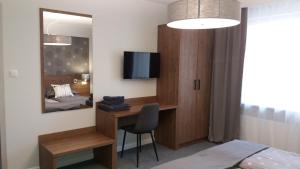 a bedroom with a bed and a desk with a television at Villa Ilava in Iława